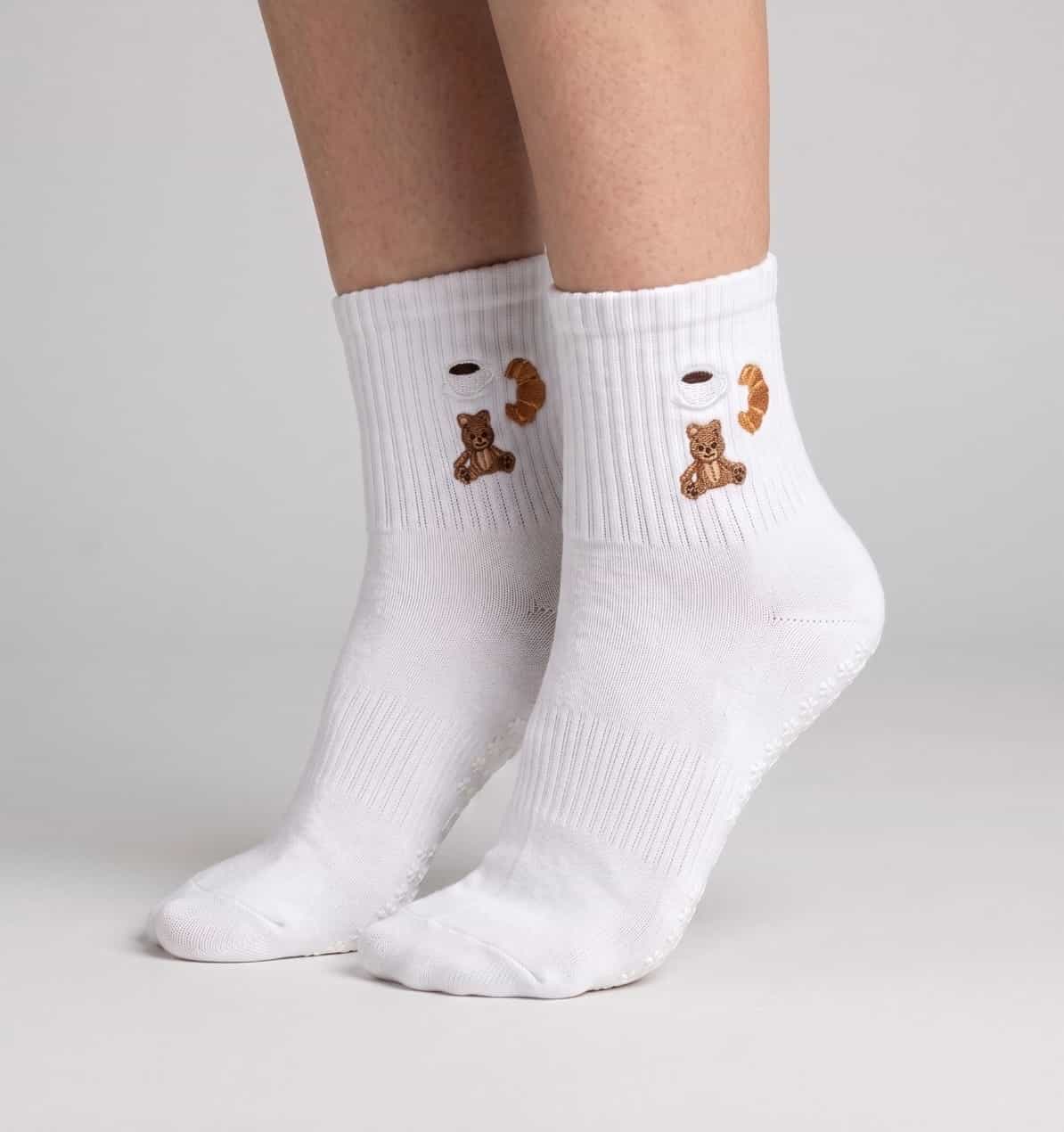 Weiße Socken mit einem Teddybären, Croissant und Caffee