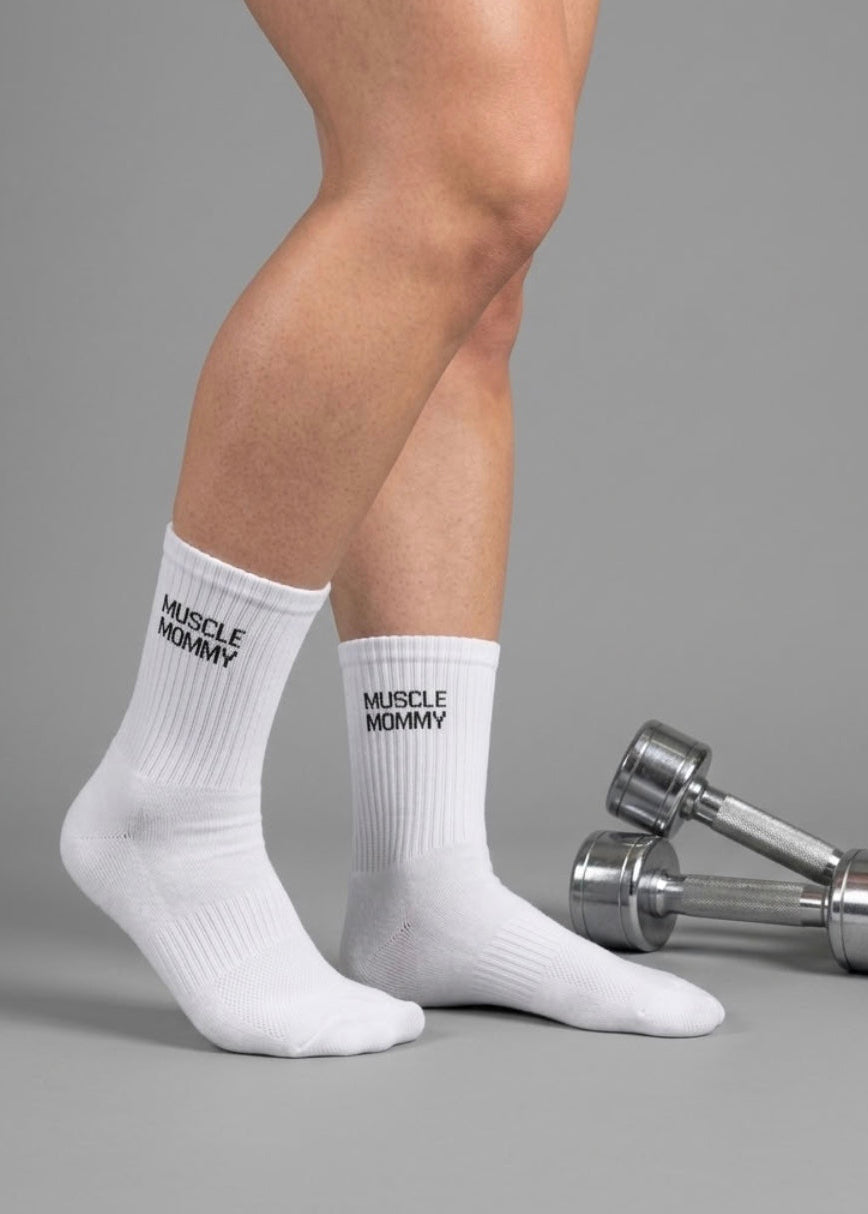 Weiße Socken in Crew Länge mit einem grauen Hintergrund und zwei silbernen Hanteln auf dem boden