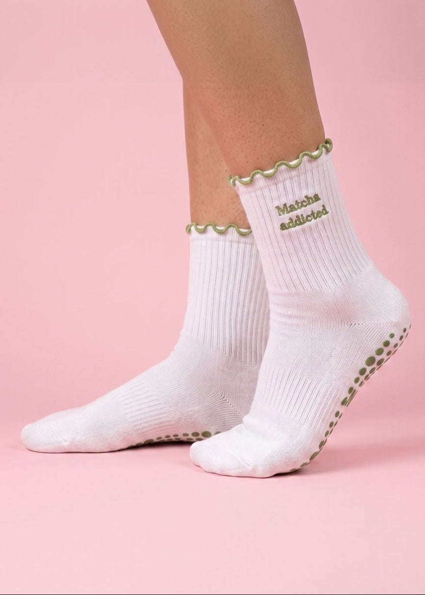 Weiße Pilates Socken mit einem grünen Rüschenrand und einer Schrift die sagt "Matcha Addicted"