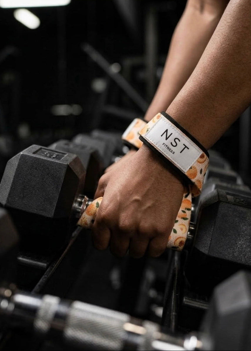 NAST Fitness Zughilfen im orangefarbenen Peach-Design beim Hanteltraining im Gym, mit gepolstertem Handgelenkband für zusätzlichen Halt beim Krafttraining.