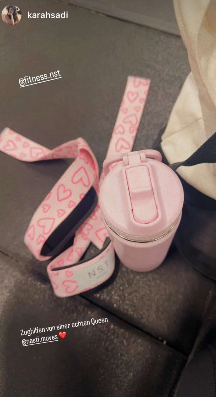 Rosa NST Fitness Zughilfen mit Herzmuster neben einer pinken Trinkflasche – stylisches Gym-Zubehör für Frauen beim Krafttraining.