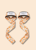 NAST Fitness Zughilfen mit verspieltem Orangen-Print und weißem Logo-Label, dekorativ auf pfirsichfarbenem Hintergrund präsentiert
