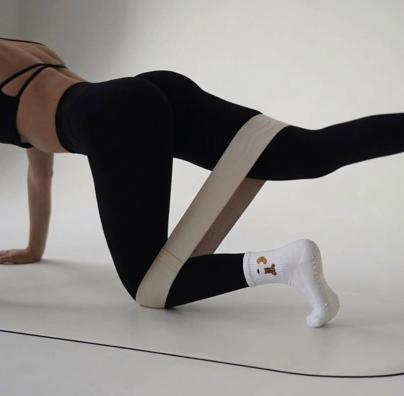Weiße Pilates Socken mit rutschfester Sohle beim Pilates Training mit Resistance Band auf der Matte