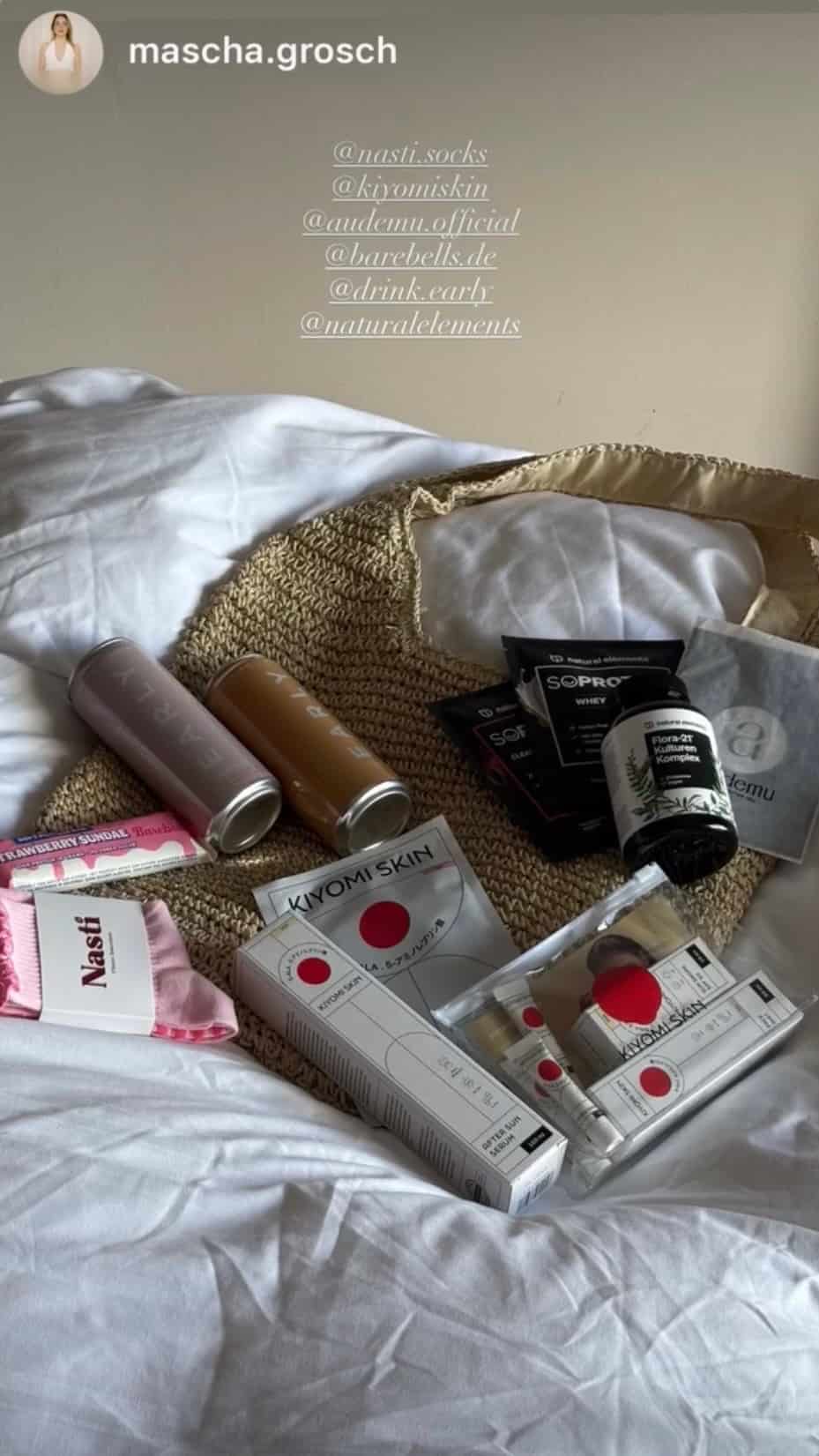 NST Pilates Grip Socks in Rosa als Teil eines Wellness- und Fitness-Goodie-Sets auf einem Bett mit Beauty-, Supplement- und Lifestyle-Produkten“