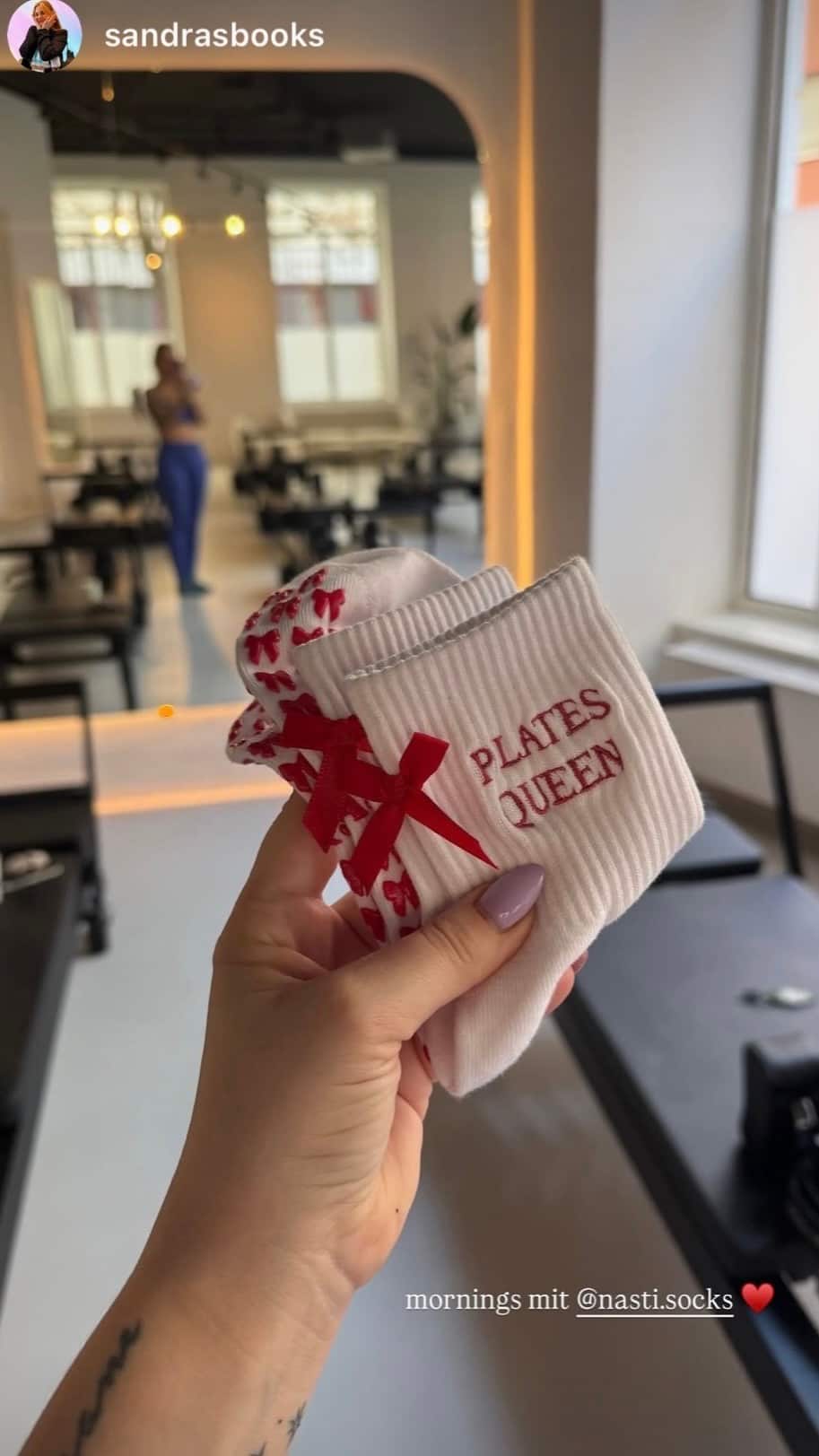 Weiße NST Pilates Grip Socks mit rotem Schleifen- und Herzdesign sowie ‚Pilates Queen‘ Schriftzug in einem Reformer-Pilates-Studio