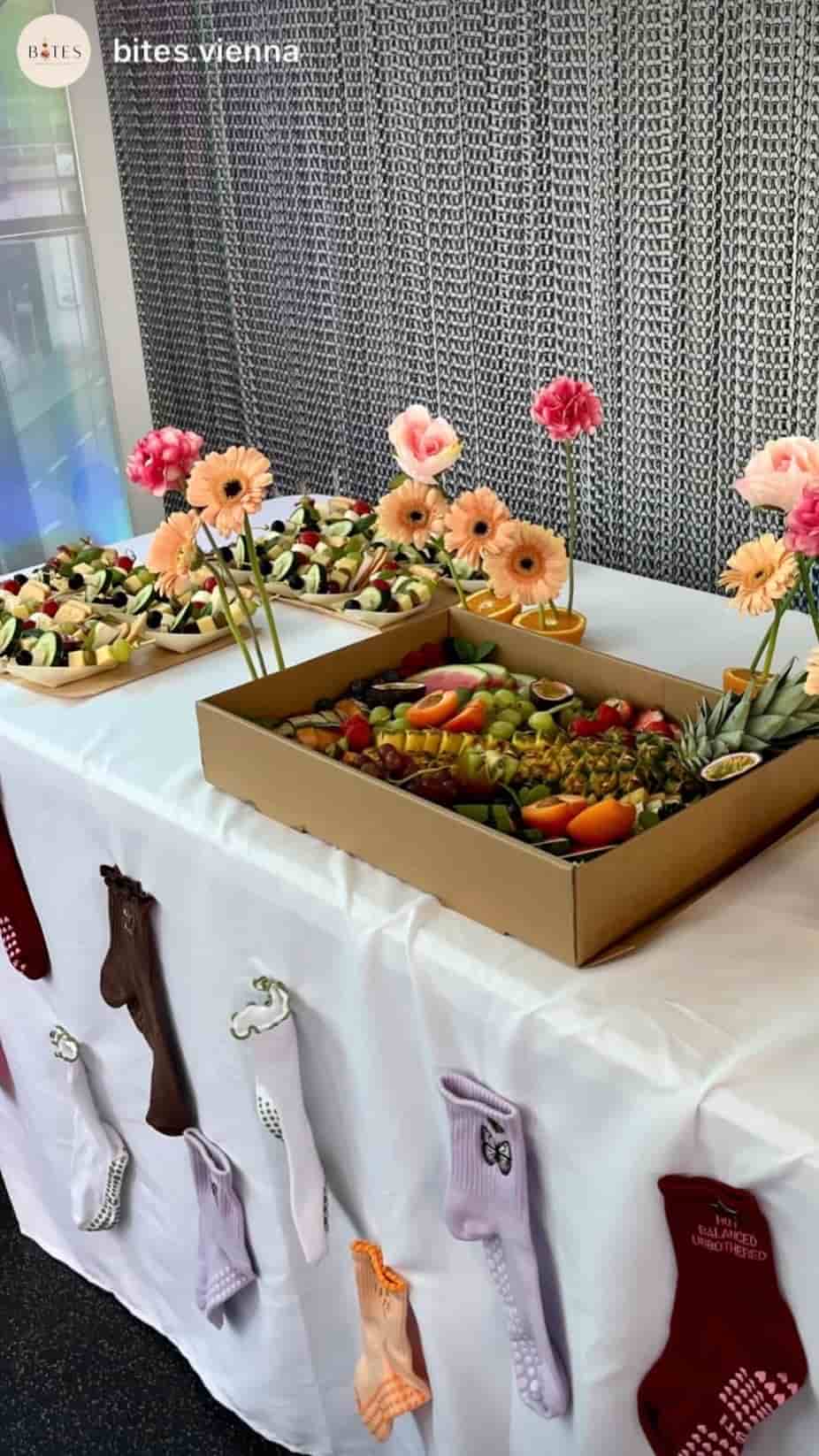 NST Pilates Grip Socks in verschiedenen Farben und Designs als Dekoration an einem Tisch mit frischem Obst und Snacks bei einem Pilates Event