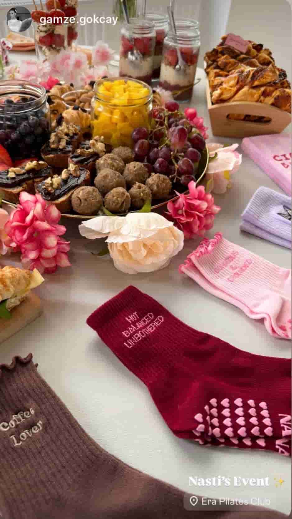 Pilates-Event mit reichhaltigem Brunch-Buffet, Blumen und verschiedenen Nasti Grip Socks in Braun, Pink und Bordeaux auf einem Tisch.