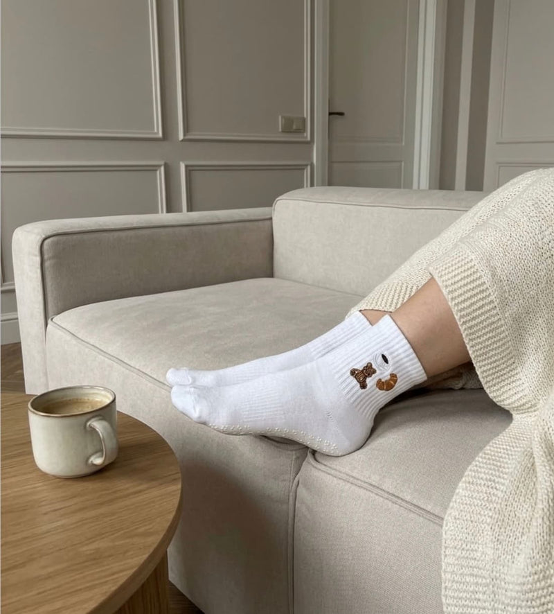 Weiße Pilates Socken mit  beim Entspannen auf einem Sofa